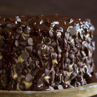 布朗尼层蛋糕上覆盖着饼干面团糖霜，巧克力糖浆在质朴的木制蛋糕架上淋上淋上淋上的巧克力糖浆。