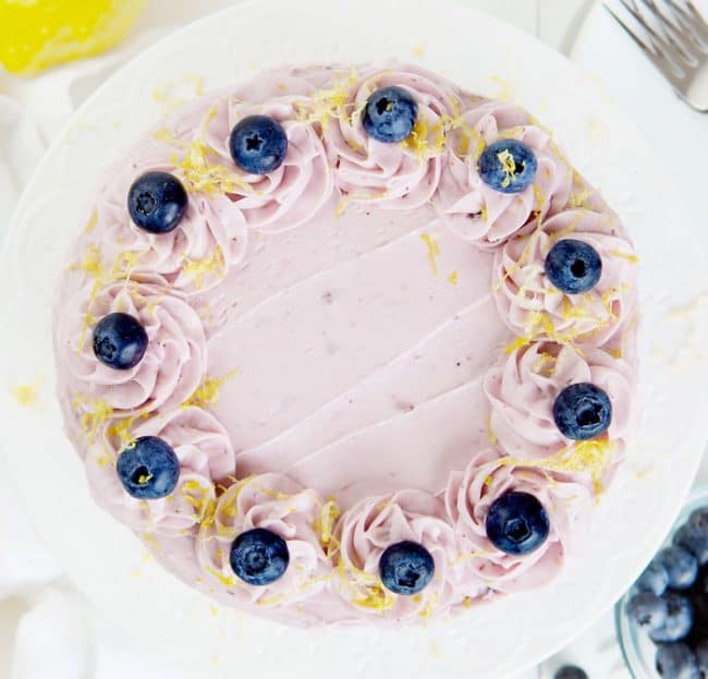 俯视柠檬蛋糕，上面覆盖着蓝莓奶油、蓝莓和柠檬皮。