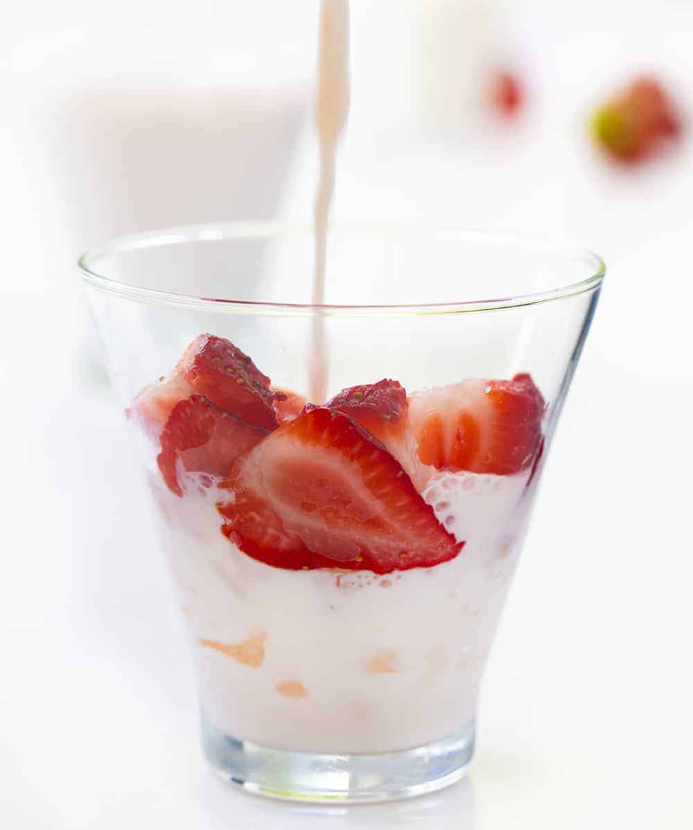 将牛奶倒入草莓和奶油牛奶玻璃用草莓和冰