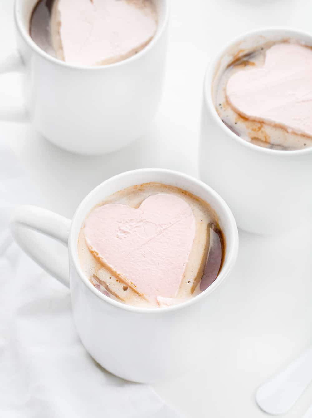 粉红色的奶油心脏在杯热的可可粉