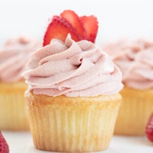 草莓ermine糖霜在用草莓的纸杯蛋糕上管道。