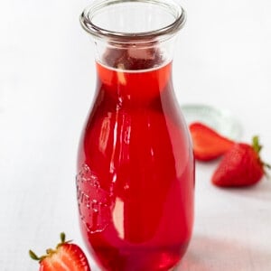 一瓶草莓简单的糖浆被草莓包围。